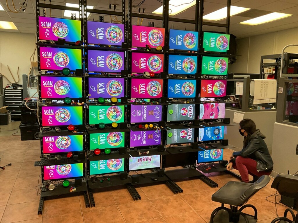 The project team works on a rack of more than 30 monitors to test media and software in the lab at Mad Systems office.