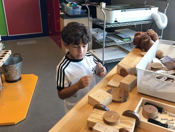 A guest creates a wooden vehicle out of pre-cut blocks, wheels, and bolts.